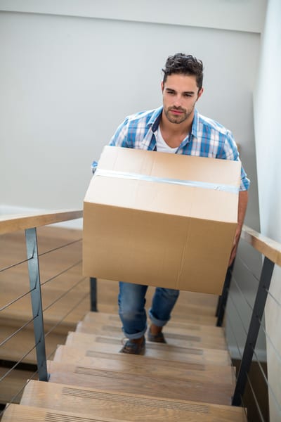 man walking up the stairs carrying a large box